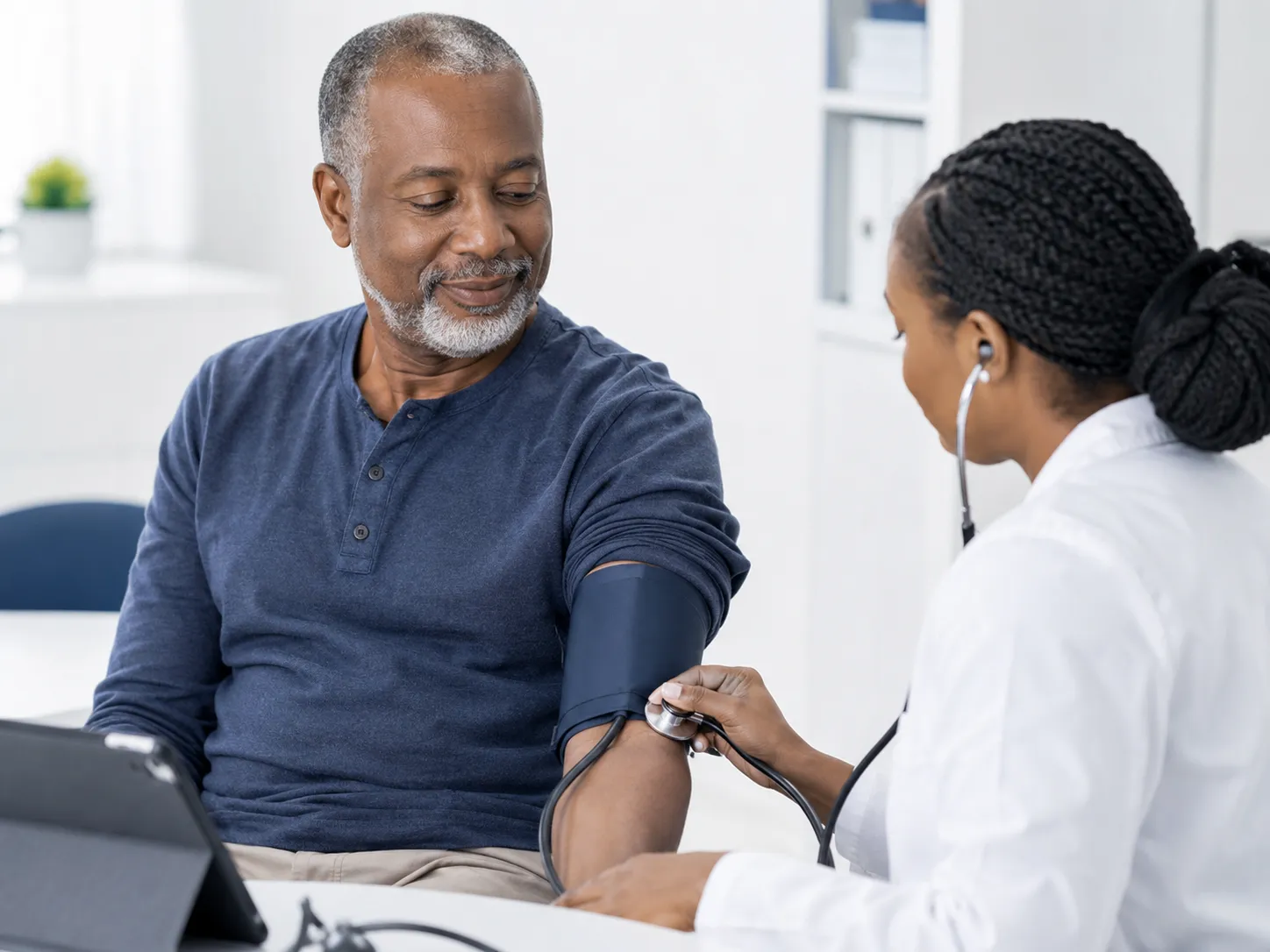 Doctor checking an adult male patient’s blood pressure during a cardiovascular health assessment